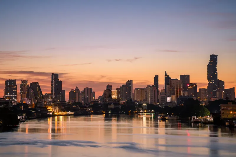 The Bangkok skyline reflected in the Chao Phraya river at dawn