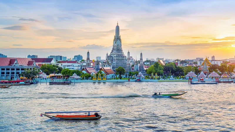 Longtail boats on the Chao Phraya river in front of Wat Arun at sunset