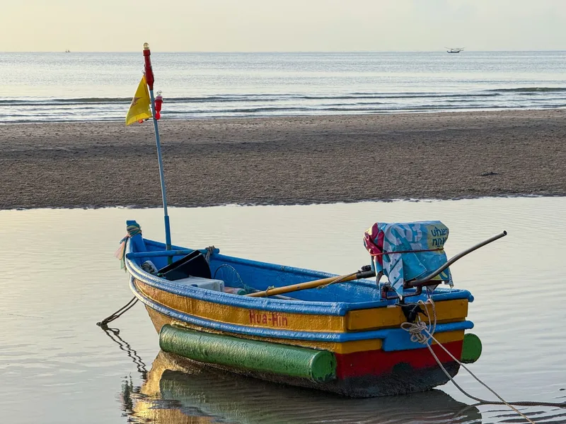 A brightly painted Hua Hin fishing boat at low tide on the beach
