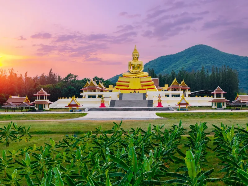 A giant golden Buddha at a temple complex below the hills near Hua Hin at sunset