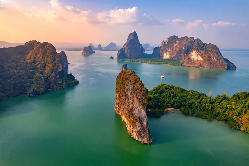 Limestone islands scattered across the green waters of Phang Nga bay at sunset