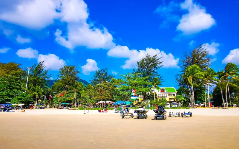Palm-fringed white sand beach with jet skis and beach umbrellas in Phuket